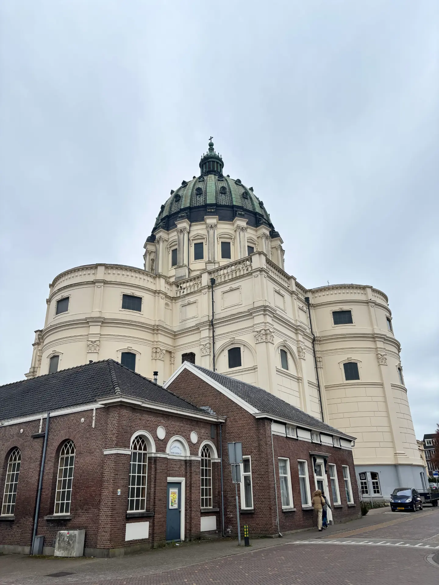 Basiliek H.H. Agatha en Barbara in Oudenbosch, gezien vanaf straatniveau met de koperen koepel boven de omliggende bebouwing