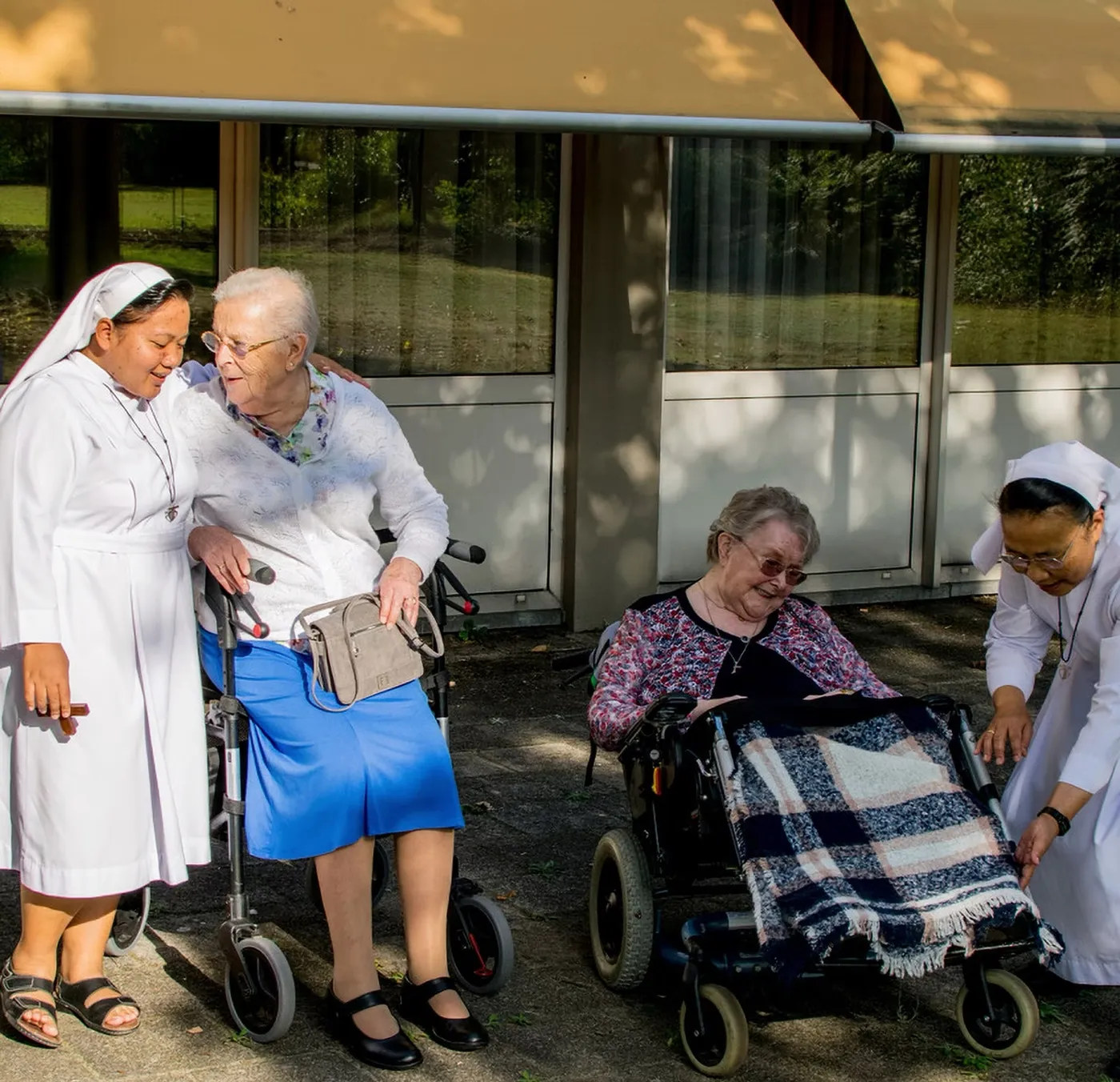 Zusters van Charitas in gesprek met oudere bewoners in de kloostertuin