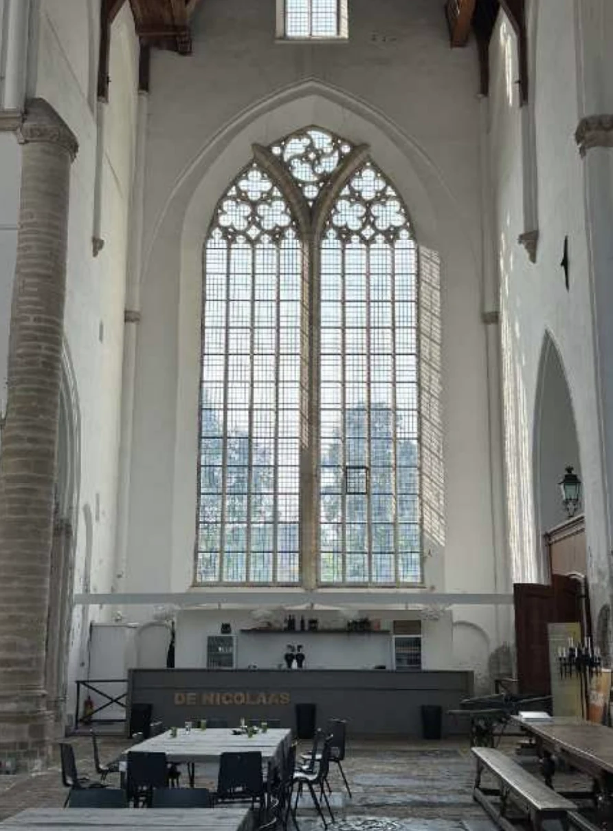 Bar en ontmoetingsplek onder het hoge kerkvenster van De Nicolaas