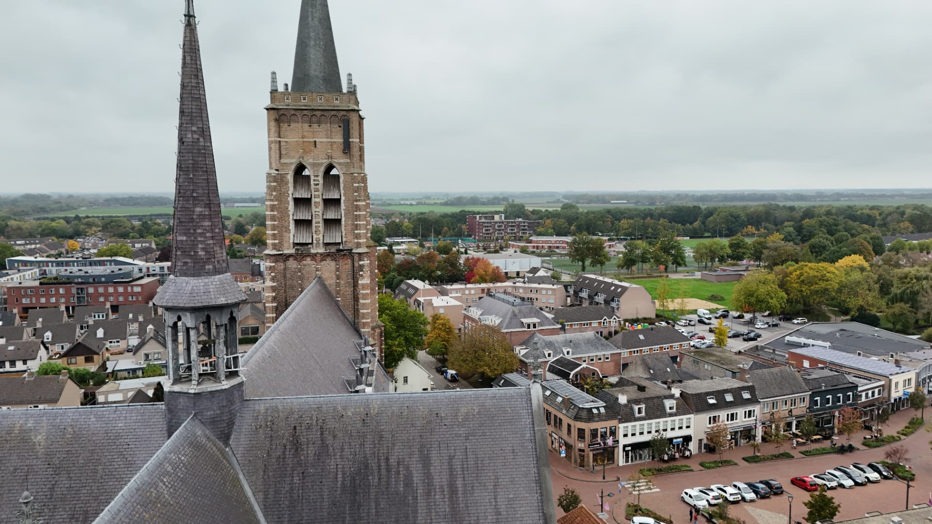Luchtfoto van een historische kerk met toren midden in een Nederlands dorpscentrum