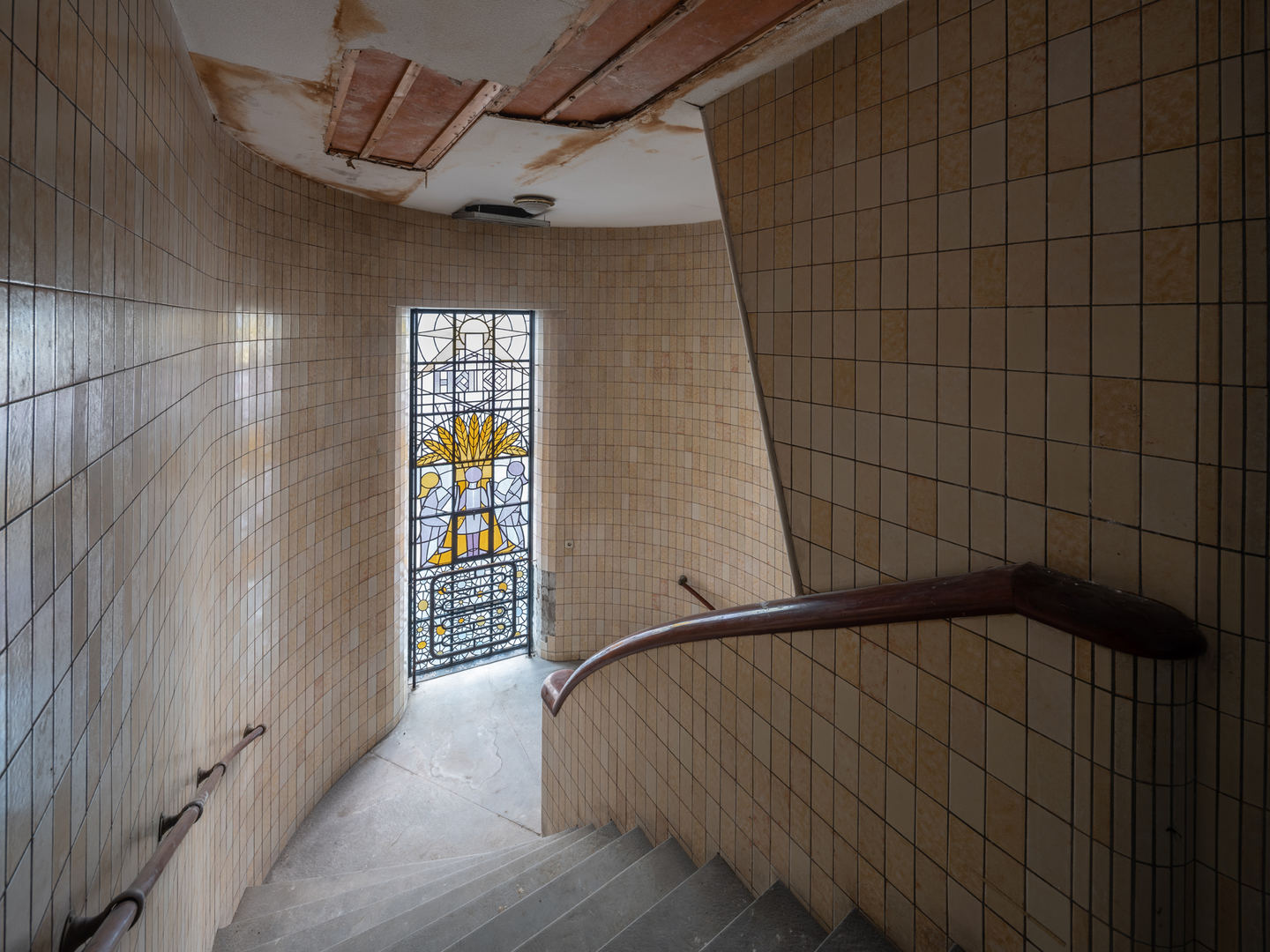 Monumentale traphal in het HAKA-gebouw met een open deur en glas-in-lood