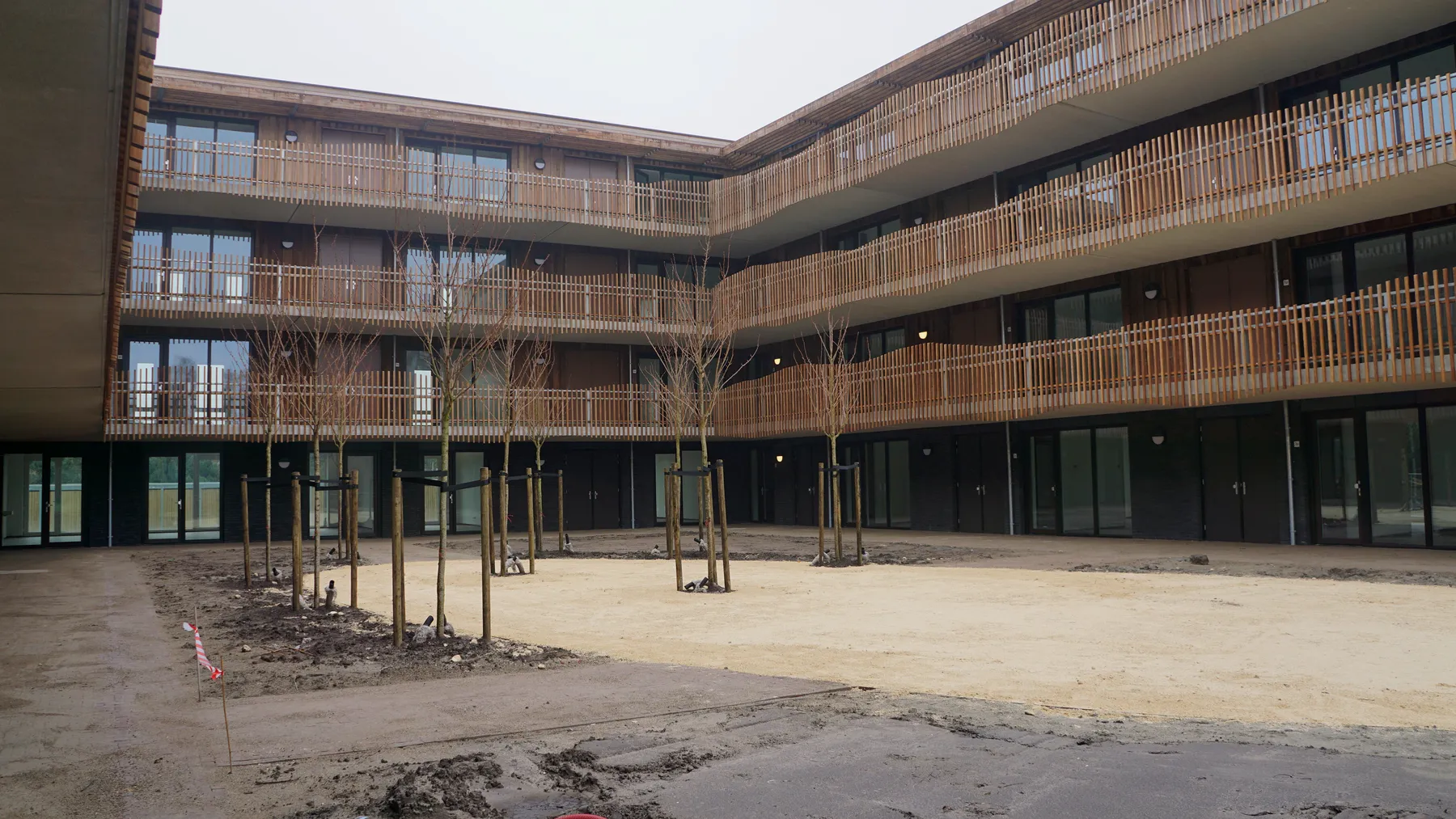 Binnenplaats van Viertien met rondom houten galerijen en jonge bomen