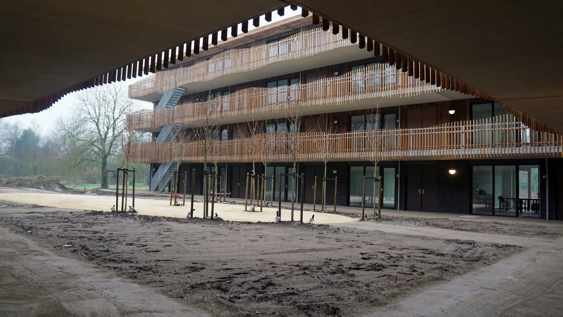 Binnenhof van Viertien met houten galerijen rondom een open, groene ruimte in aanleg